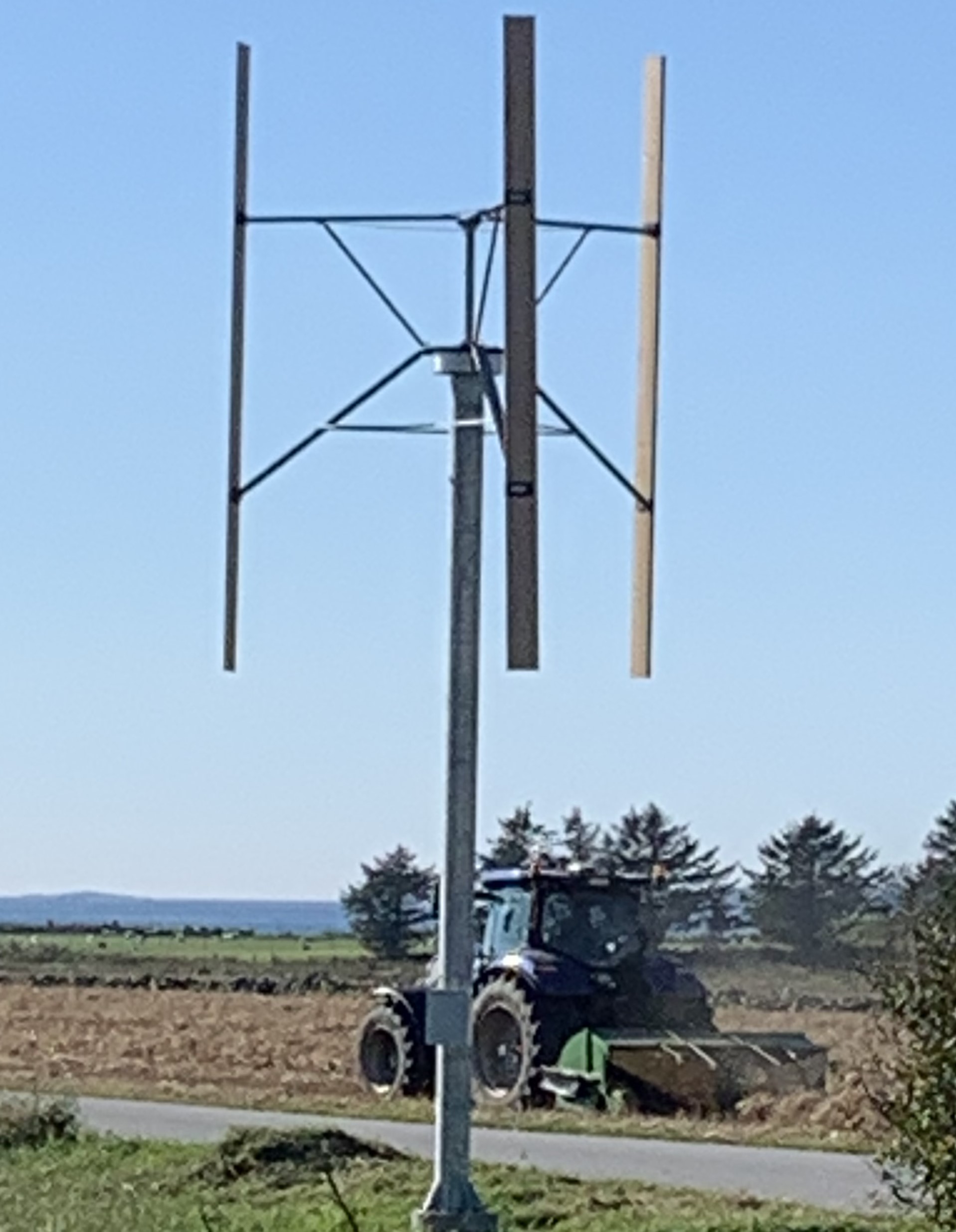 Carnetic 316 wind turbine on a farm with a tractor in the background